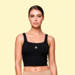 Mujer usando un top deportivo negro de cuello cuadrado con un pequeño logo blanco de VA